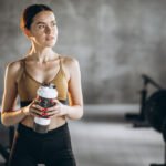 Žena pije vodu nakon treninga u teretani