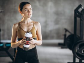 Žena pije vodu nakon treninga u teretani
